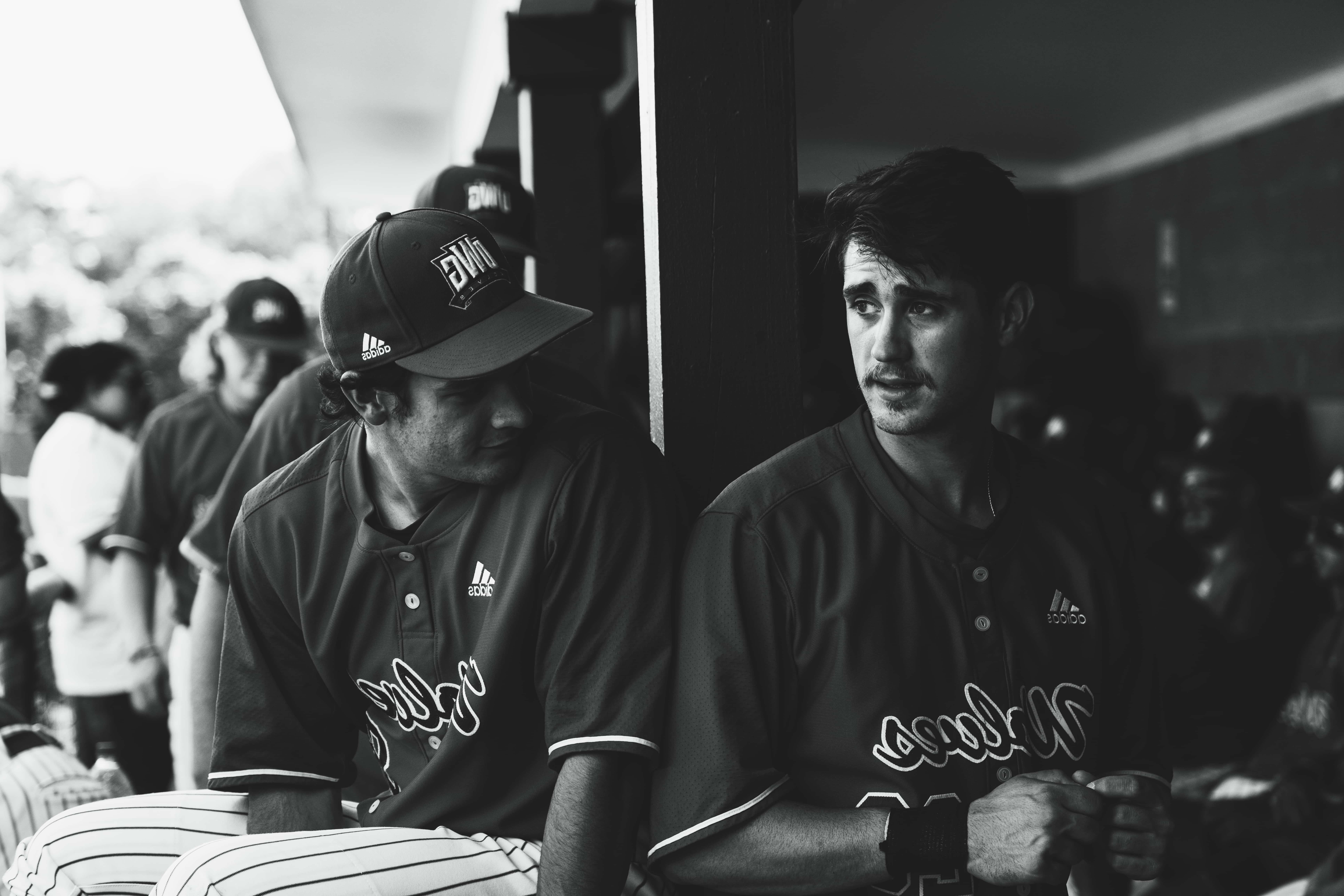 Baseball players sitting together in the dugout.